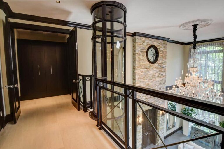 PVE37 cylindrical vacuum elevator on upper landing overlooking a grand foyer with chandelier