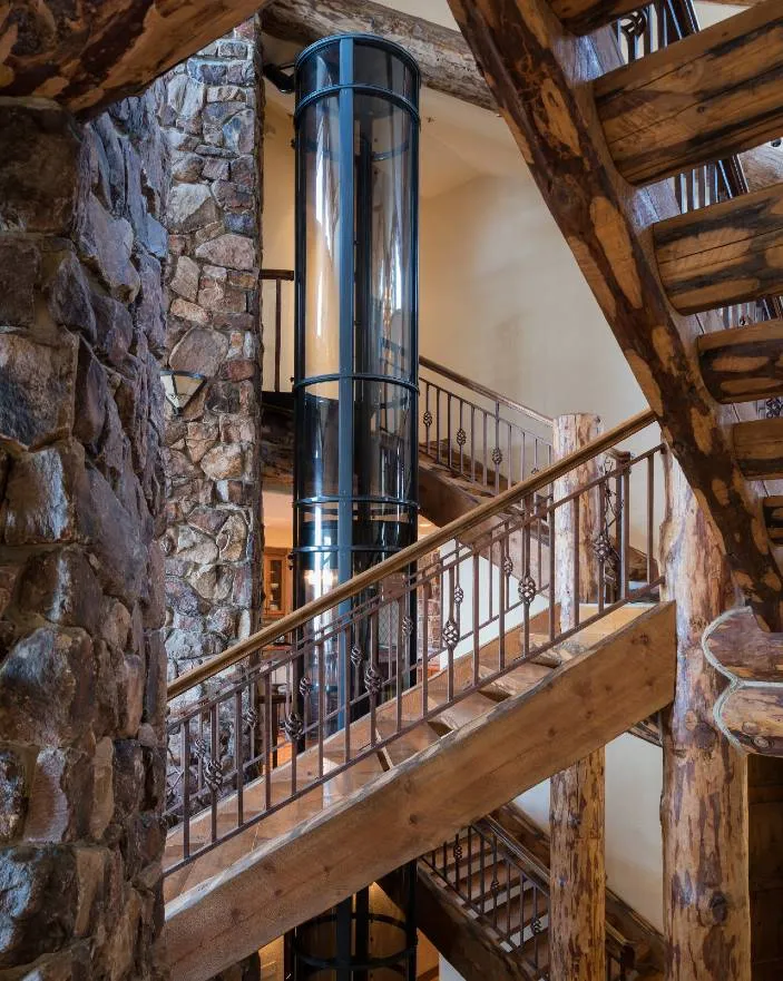 PVE37 pneumatic vacuum elevator with glass tube installed beside a rustic log staircase