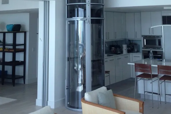 Clear tube pneumatic vacuum elevator installed between living room and modern kitchen