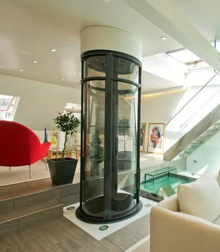 Round PVE pneumatic vacuum elevator with glass tube installed in a modern living room by a staircase