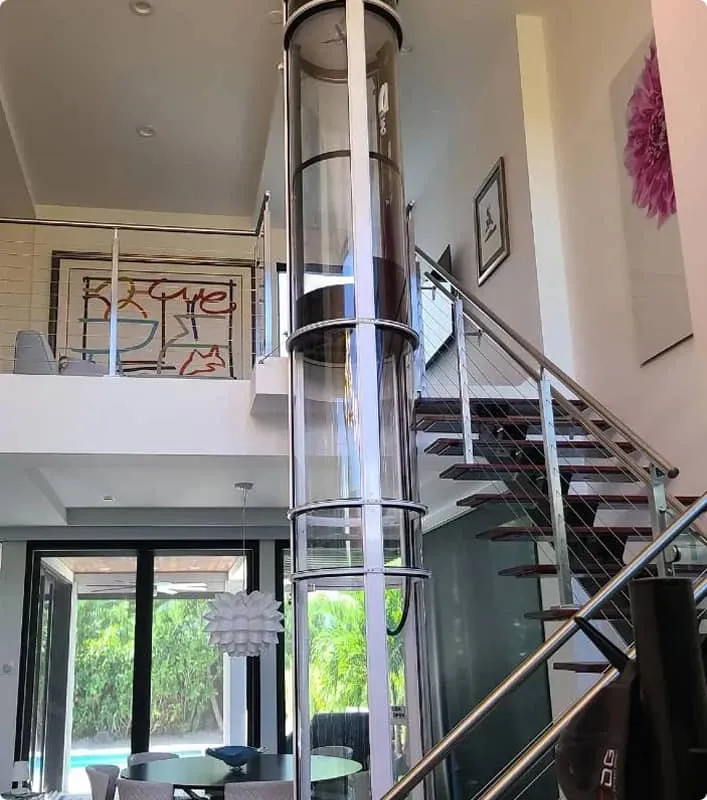 PVE30 pneumatic vacuum elevator installed beside a modern floating staircase in a two story home