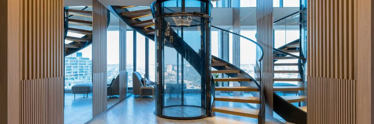 Round pneumatic vacuum elevator installed beside a spiral staircase in a modern penthouse
