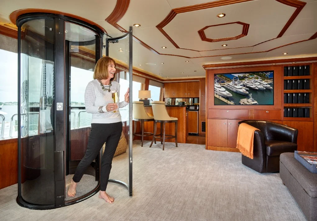Woman exiting a round vacuum elevator installed in a luxury yacht lounge