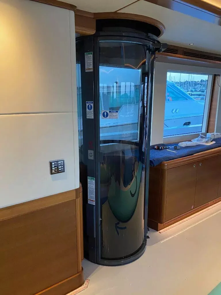 PVE pneumatic vacuum elevator installed inside a yacht with marina view through the window
