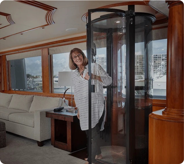 Smiling woman opening the door of a PVE home elevator aboard a yacht